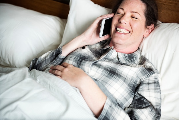 Una mujer llamando a alguien en la cama