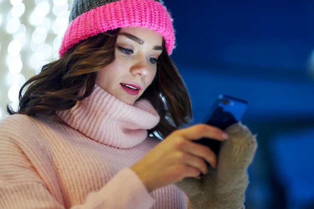 Mujer llamando felicitar con Navidad o año nuevo. Mujer con smartphone en feria festiva