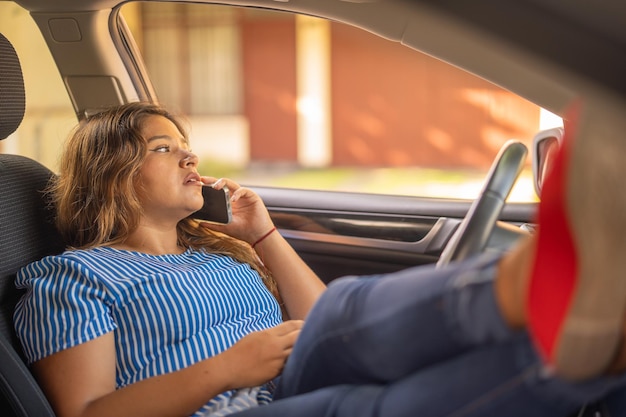 Foto mujer llamando a la grúa porque su coche se averió acostada con los pies en el asiento del coche