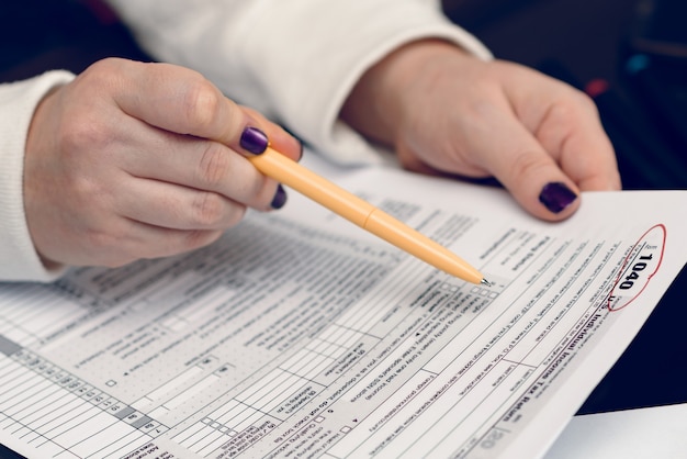 Mujer llena el formulario de impuestos trabajando con documentos de impuestos Formulario 1040 Formulario de declaración de impuestos sobre la renta de las personas físicas