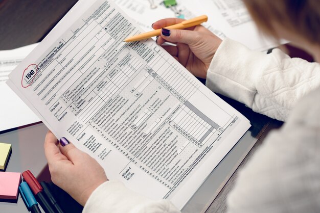 Mujer llena el formulario de impuestos trabajando con documentos de impuestos Formulario 1040 Formulario de declaración de impuestos sobre la renta de las personas físicas