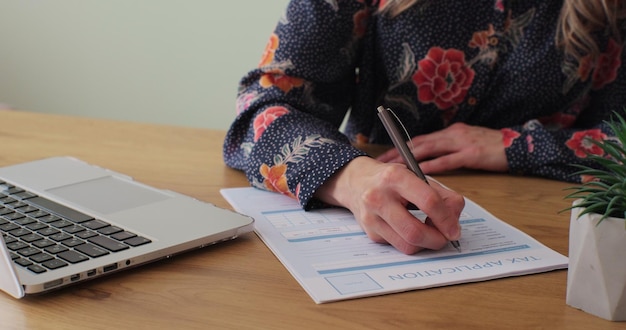 Mujer llenando y firmando formulario de impuestos en el escritorio Tecnología empresarial y concepto de personas mujer con computadora portátil