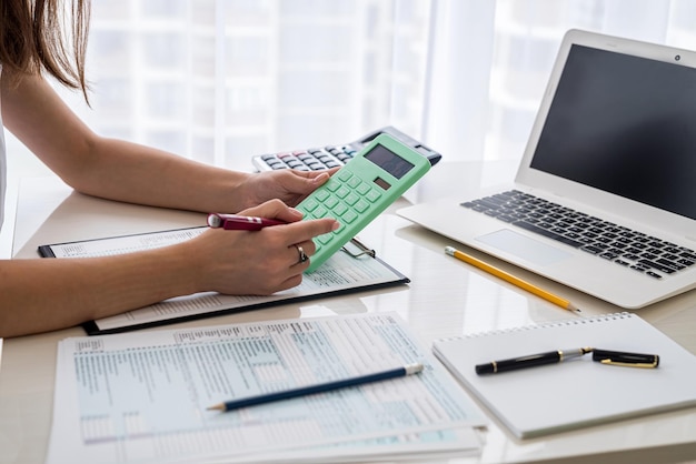 Mujer llenando el formulario de impuestos de EE. UU. Con una computadora portátil y una calculadora en la oficina