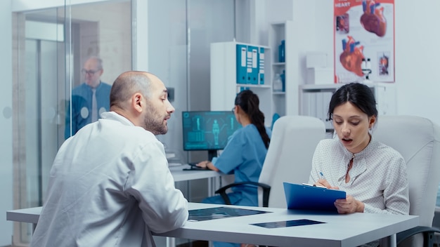 Mujer llenando formularios, preguntando al médico sobre algo que no sabe. Atención médica en un hospital moderno o clínica privada, prevención de enfermedades y consulta en consultorio médico, tratamiento, medicación, diagnóstico.