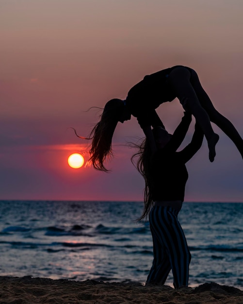 Foto mujer llevando a una amiga en la playa durante la puesta de sol