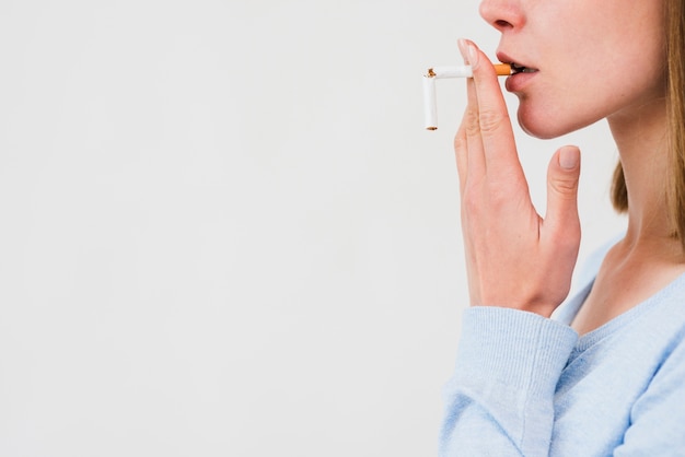 Mujer llevando cigarrillo roto sobre fondo blanco