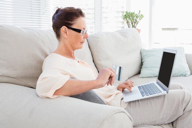 Mujer llevando portátil mientras descansa en el sofá