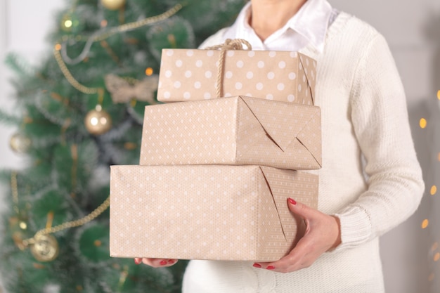 Mujer llevando regalos de Navidad apilados