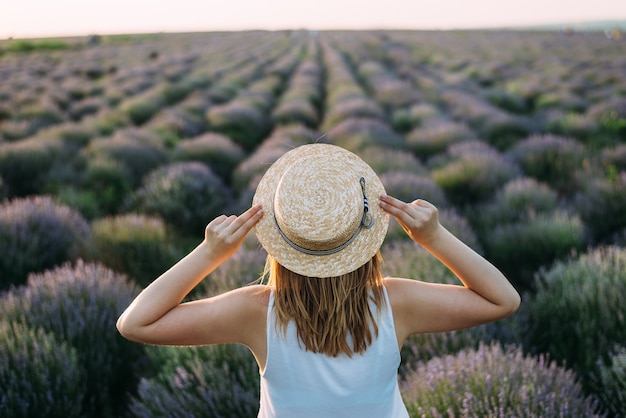 Mujer, llevando, sombrero de paja, posar, en, campo lavanda