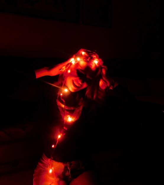 Foto mujer con luces de navidad iluminadas por la noche