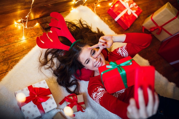 Mujer con luces de navidad y regalos en suelo