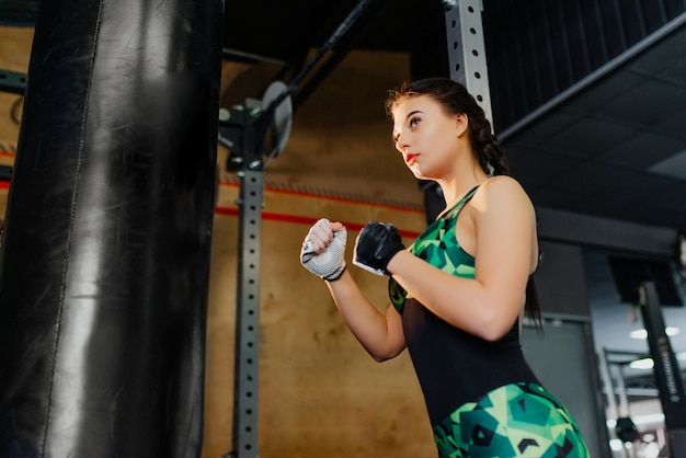 mujer luchadora en gimnasio listo para trabajar con bolsa de boxeo. Modelo de fitness.