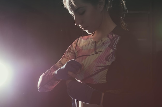 Mujer luchadora poniéndose guantes de boxeo preparándose para el entrenamiento