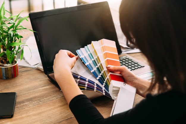 Mujer en el lugar de trabajo eligiendo cartas de papel de colores