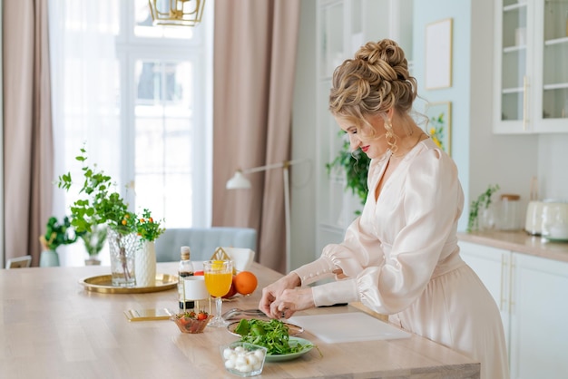 Mujer lujosa feliz prepara ensalada ligera con fresas y rúcula