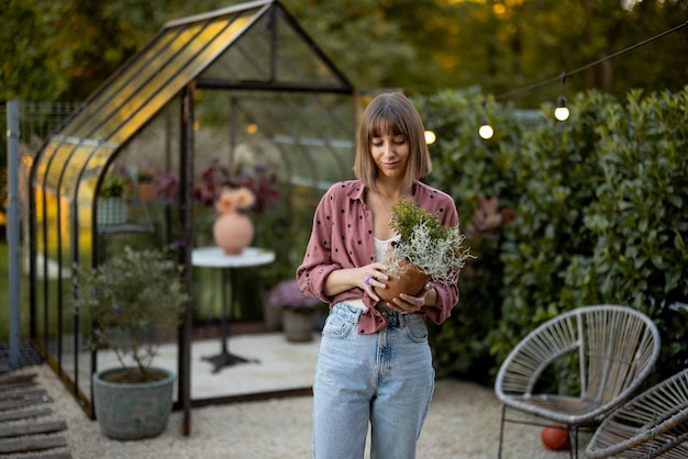 mujer, con, maceta, en, jardín, con, invernadero, atrás