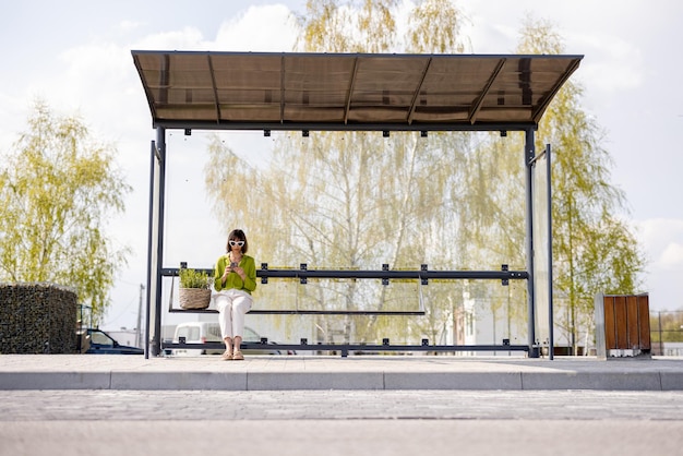 Mujer con maceta en la parada de autobús moderna