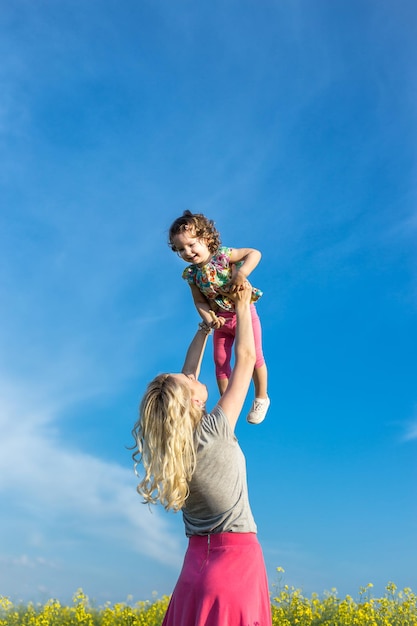 Foto una mujer madre juega con un niño en la naturaleza levantándolo y lanzándolo en ella