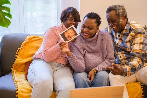 Mujer madre soltera que muestra la ecografía virtualmente con sus orgullosos padres