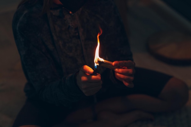 Mujer madura adulta haciendo yoga en casa salón prende fuego con incienso de palo de palo santo