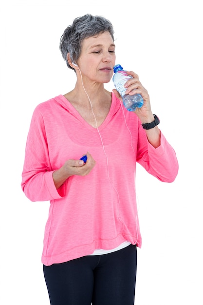 Mujer madura agua potable mientras escucha música