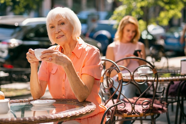 Mujer madura alegre relajarse al aire libre con una taza de café caliente