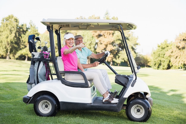 Mujer madura apuntando mientras está sentado en el carrito de golf