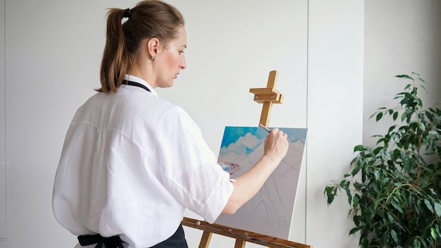 Mujer madura artista pinta cielo paisaje sobre lienzo de caballete