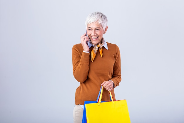 Mujer madura con bolsas de compras y teléfono móvil