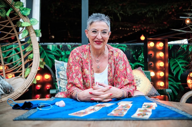 mujer madura con canas usando cartas del tarot para predecir el futuro