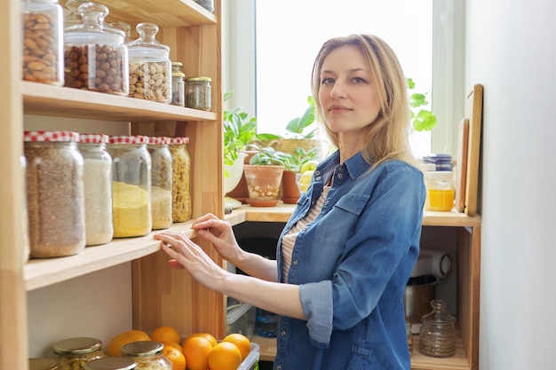 mujer madura, en casa, en, cocina, en, despensa, retrato, de, ama de casa, hembra, mirar cámara del juez