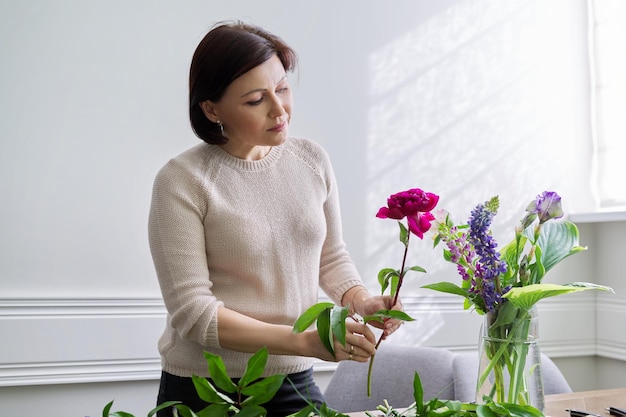 Mujer madura en casa con flores de primavera