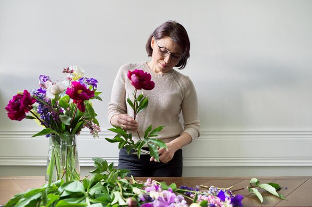 Mujer madura en casa con flores de primavera