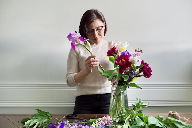 Mujer madura en casa con flores de primavera