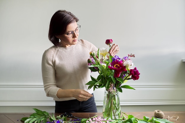 Mujer madura en casa con flores de primavera