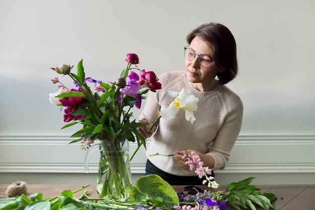 Mujer madura en casa con flores de primavera