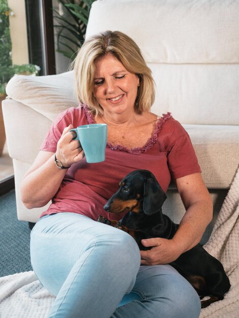 Mujer madura caucásica con una taza de café con su perro Dachshund