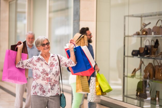 Una mujer madura en el centro comercial yendo de compras con su marido - senior hiolding algunas bolsas sonriendo