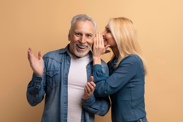 Foto mujer madura compartiendo secreto con su marido fondo beige