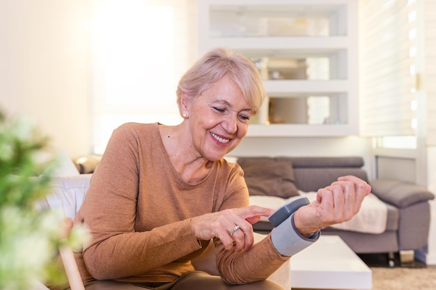 Foto mujer madura comprobando la presión arterial vista en primer plano de un monitor de presión arterial en la mano tonometro digital en la mano humana retrato de una mujer mayor midiendo su presión arterial