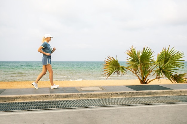 Mujer madura corriendo a lo largo de la orilla de la playa Mujeres mayores haciendo deporte Estilo de vida saludable y activo