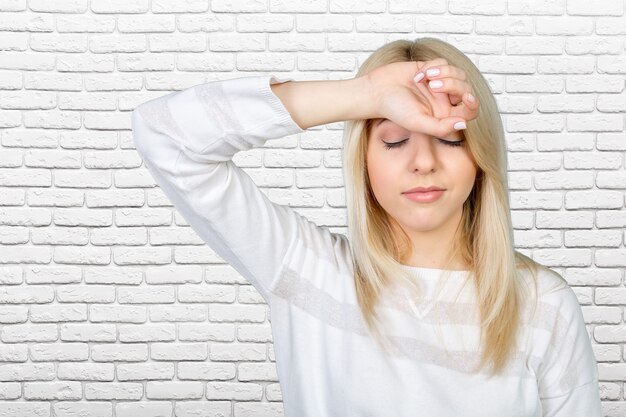 Mujer madura deprimida tocando la frente y manteniendo los ojos cerrados