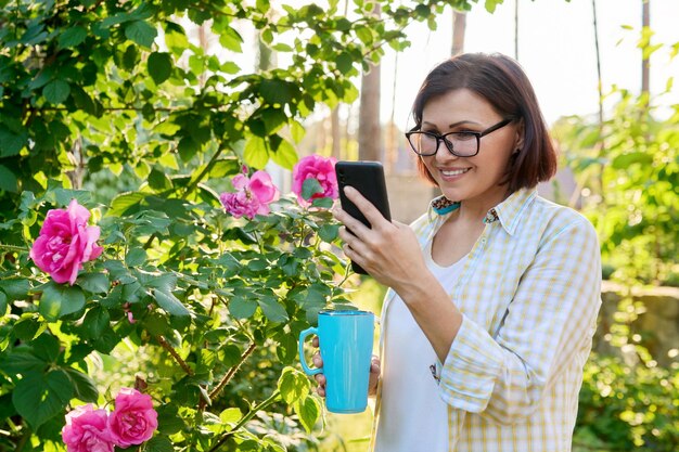 Mujer madura descansando en el patio trasero usando un teléfono inteligente para videollamadas