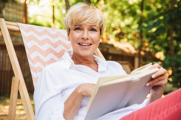 Mujer madura emocionada leyendo un libro