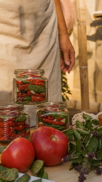 mujer madura enlatando tomates secos con albahaca y ajo en el patio trasero al atardecer