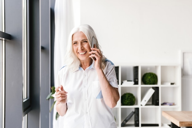 Mujer madura feliz adentro en la oficina