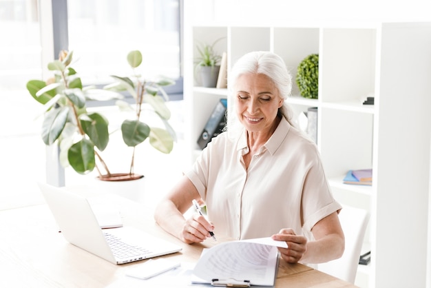 Mujer madura feliz escribiendo notas.