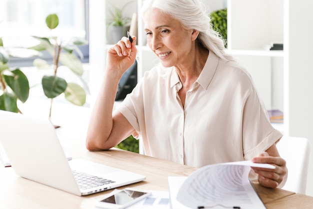 Mujer madura feliz escribiendo notas.