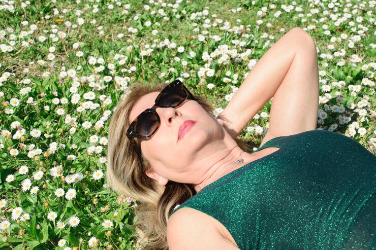 Mujer madura feliz en la hierba con marguerites Menopausia y concepto del día de la madre