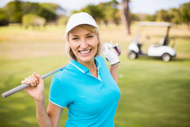 Mujer madura feliz que lleva el club de golf